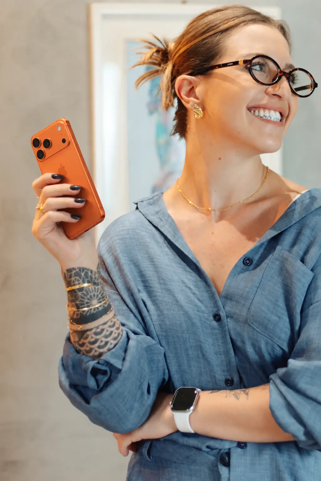 Isabela Ranú de camisa azul, com celular na mão, olhando para o lado